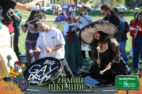 A costumed drum group performs beside their sign.