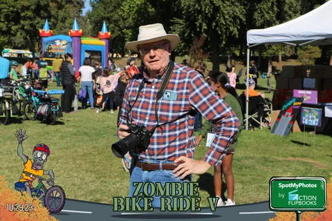 An older man in a plaid shirt and hat smiles for the camera.