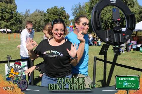 Three women wave energetically for the camera at a photo booth station.