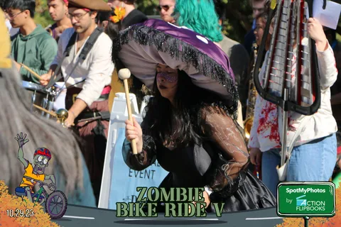 A performer in an elaborate purple headdress drums energetically.