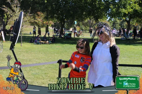 Two women in ghost and striped costumes stand behind a rope barrier.
