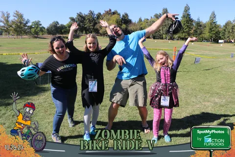 A family of four jumps together with arms raised in joyful celebration.