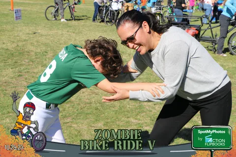 A woman and boy in a green jersey laugh during a playful wrestling match.