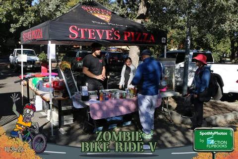 People gather at the Steve's Pizza food tent under the trees.