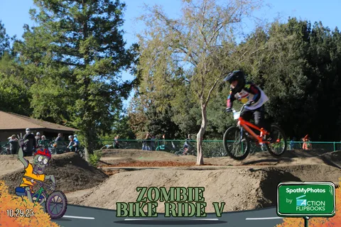 A BMX rider soars over a dirt jump on the park track.