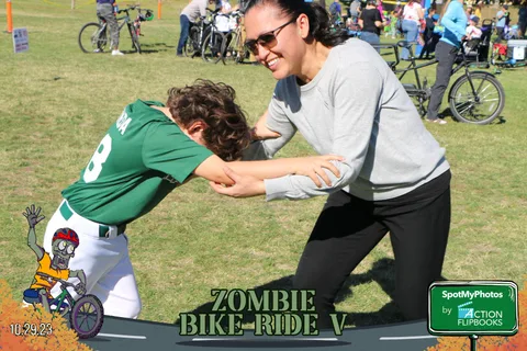 A woman and a boy in a green jersey play wrestle and laugh together.