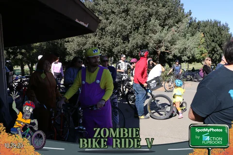 A man in a yellow Wario-style costume stands with others near the gazebo.