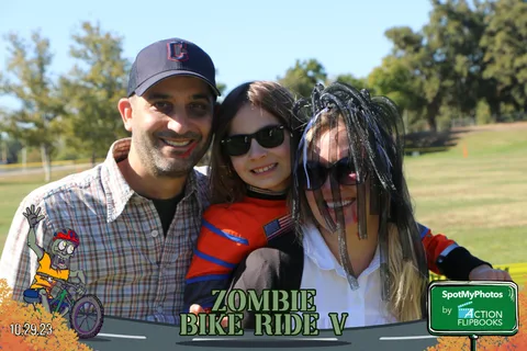 A man embraces two women, one wearing a dreadlock wig and face paint.