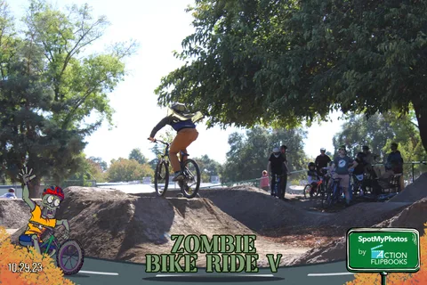 A BMX rider catches air over a dirt jump against a clear sky.
