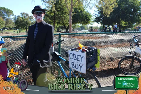 A man in a suit and skull mask pulls a cart marked with an OBEY sign.