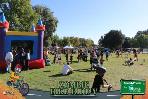 A colorful inflatable bounce castle stands in the park with kids playing nearby.