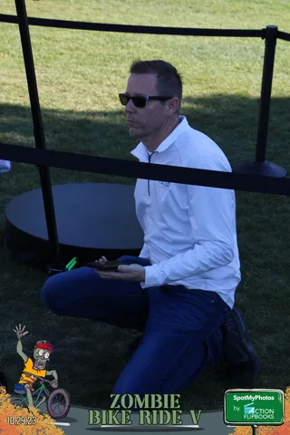 A man in sunglasses is seen through the dark bars of event equipment.