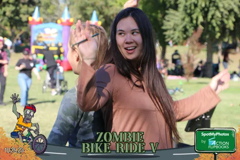A woman play-acts scaring the camera near a colorful bounce house.
