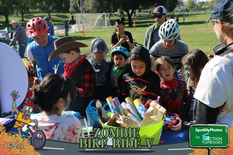 Kids gather at a festival booth while adults in cowboy hats look on.