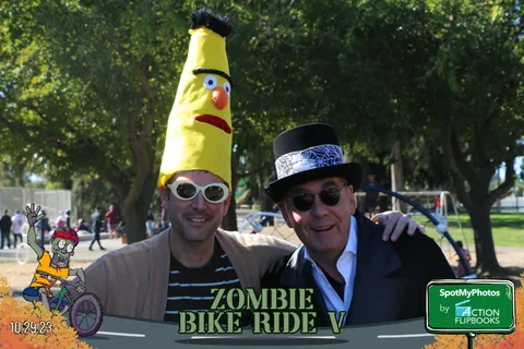 A man in a banana costume poses with a friend in a dark suit and hat.