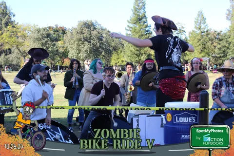 A witch hat performer sings with a raised arm at the finish line.