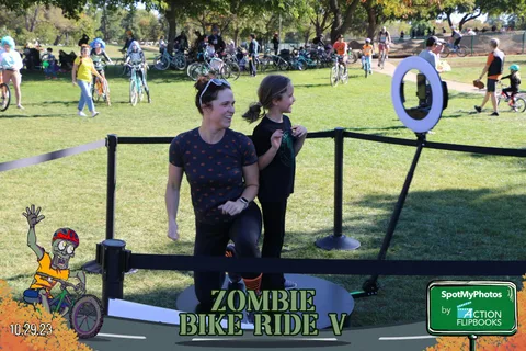Two women walk toward a ring toss game booth, seen from behind.
