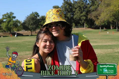 A couple smiles closely together, one wearing a yellow bucket hat.
