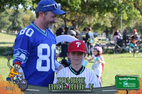 A father and son in sports jerseys smile together outdoors.