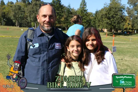 A man poses with two girls, all smiling at the camera.