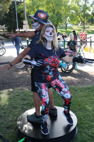 A couple in skull face paint dance together, arms outstretched.