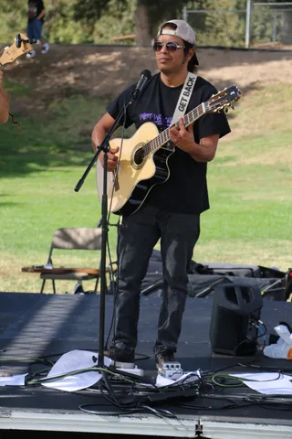 A performer's lower body is visible on the dark festival stage.