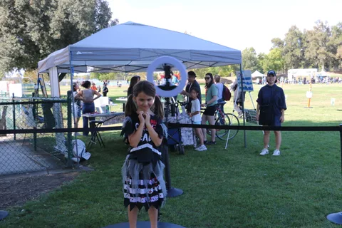 A girl in a dark costume stands under a white event tent.