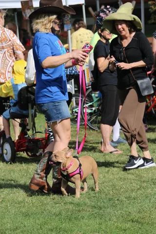 Two women in festive hats share a laugh with a pink prop.