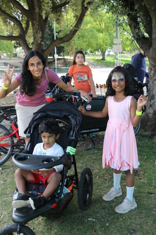 A woman and a face-painted girl flash peace signs near the bike racks.
