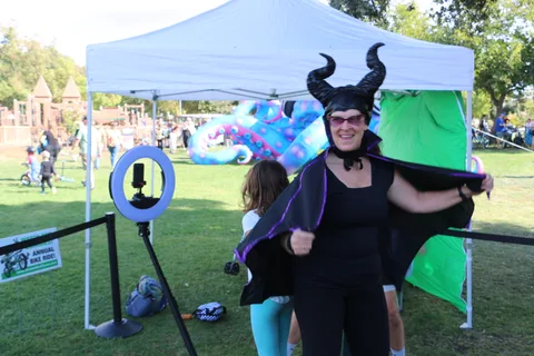 A woman in an elaborate horned dragon costume with black wings poses for the camera.