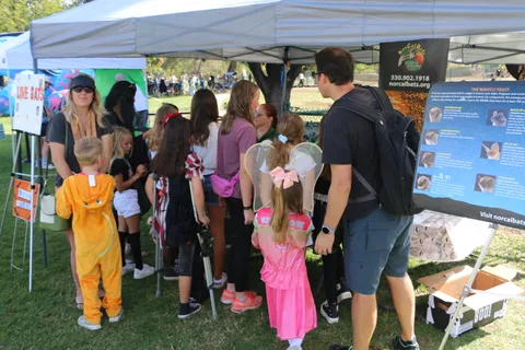 Families gather at an informational booth with costumed kids.