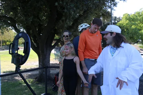 A costumed family gathers near a photo booth staffed by someone in a white lab coat.