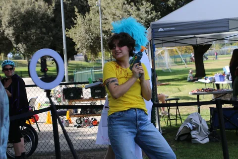 A man and a woman in a colorful wig pose at the festival photo booth.