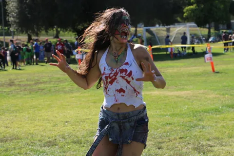 A zombie-painted performer twirls mid-dance, hair flying.