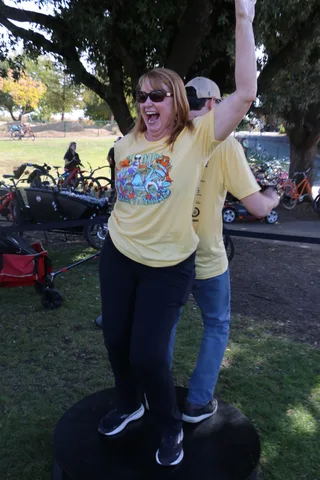 A woman raises her fist and cheers near the bike racks.