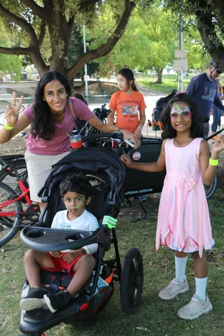 A woman and a young girl with face paint pose making peace signs.