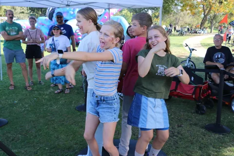 A girl laughs with arms outstretched among friends at the festival.