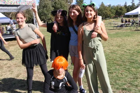 A group including a child in an orange wig poses together outdoors.