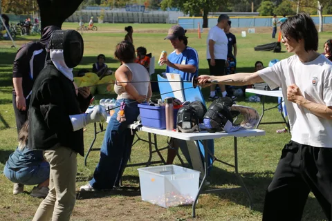 Two people set up an archery target activity at a festival booth.