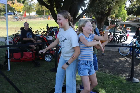 Two girls laugh together near the bike corral at the festival.