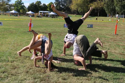 Three zombie-painted performers cartwheel in unison across the field in front of the sponsor sign.