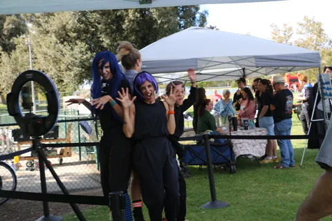 A group in colorful wigs waves at the festival's photo booth.