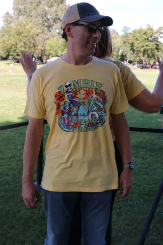 A man in a cap and sunglasses smiles broadly at the camera.