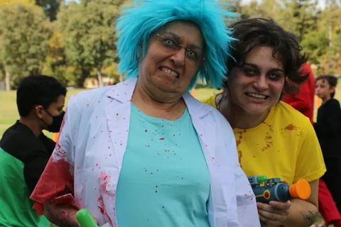 Two women in bloody mad-scientist costumes grin widely for the camera.