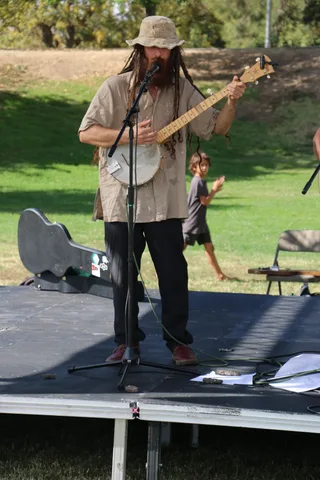A musician in a bucket hat plays banjo into the microphone.