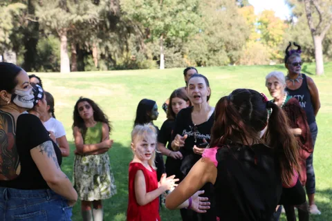 A costumed group laughs together, including a child wearing a mask.