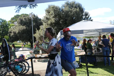 A woman with zombie face paint and a man with a baseball over one eye strike a scare pose for the camera.