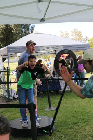 A boy in a green jersey raises his hand to high-five at the festival.