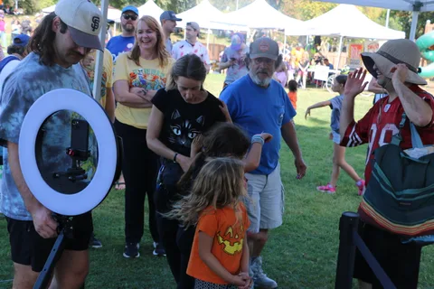 A small crowd gathers near festival photo booth equipment.