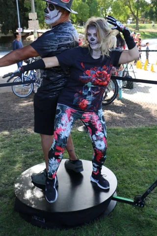 A couple in skull face paint embrace in a dramatic dip pose.